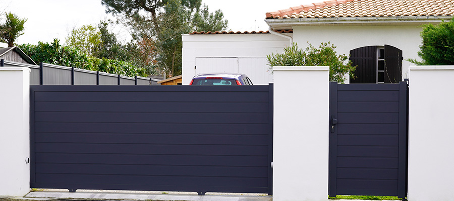 Portail de couleur noir en contraste avec la façade blanche de la maison